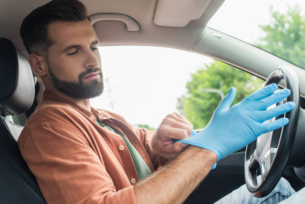 Young driver wearing latex glove in car  - Foto, Imagem