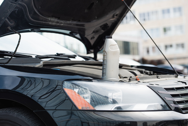 Láhev motorového oleje na auto s otevřenou kapotou venku  - Fotografie, Obrázek
