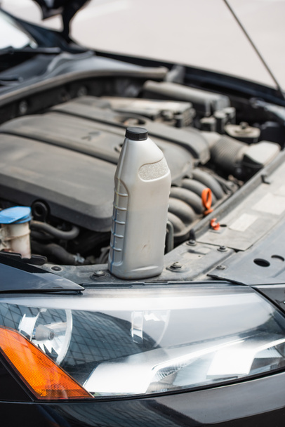 Bottle of motor oil on car on blurred background outdoors  - Foto, Imagen