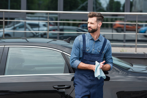 Mechanic in overalls holding rag near auto outdoors  - Foto, Bild