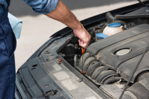 Cropped view of mechanic checking oil in motor of car  - Φωτογραφία, εικόνα