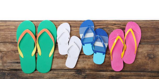 Different stylish flip flops on wooden table against white background, top view - Foto, Bild