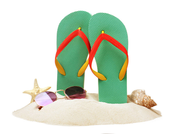 Turquoise flip flops in sand, sea shell, starfish and sunglasses on white background - Photo, image