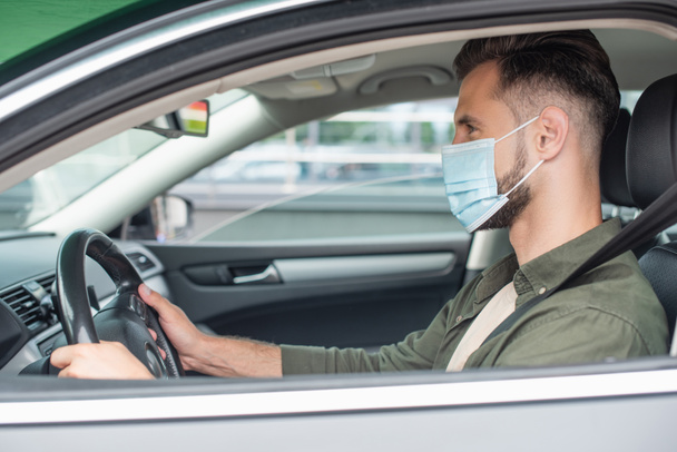 Side view of man in medical mask driving car  - Foto, Imagen