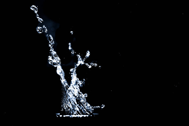 Salpicando agua sobre un fondo negro. El agua salpica sobre un fondo negro. abstracto de agua difusa - Foto, Imagen