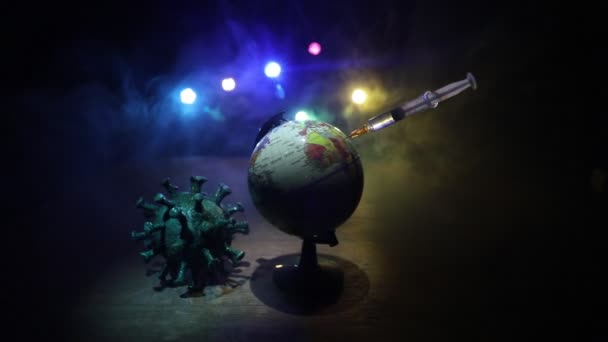 Corona virus Vaccine concept with syringe and green Corona virus novel miniature. Vaccine Concept of fight against coronavirus. Creative decoration with fog and backlight. Selective focus - Footage, Video