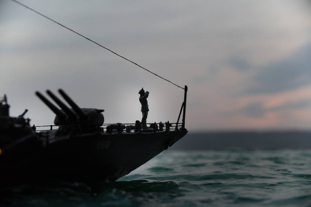 Σχέδιο πολέμου. Σκηνή νυχτερινής μάχης στη θάλασσα. Δραματική επίδραση τονισμένων νεφών. Η σιλουέτα του πολεμικού πλοίου το ηλιοβασίλεμα. Μικρογραφία δημιουργική διακόσμηση τραπέζι. Επιλεκτική εστίαση - Φωτογραφία, εικόνα