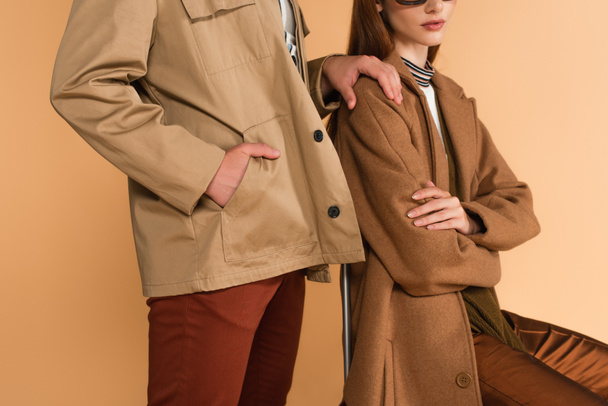 cropped view of man touching shoulder of stylish woman while standing with hand in pocket isolated on beige - Foto, immagini