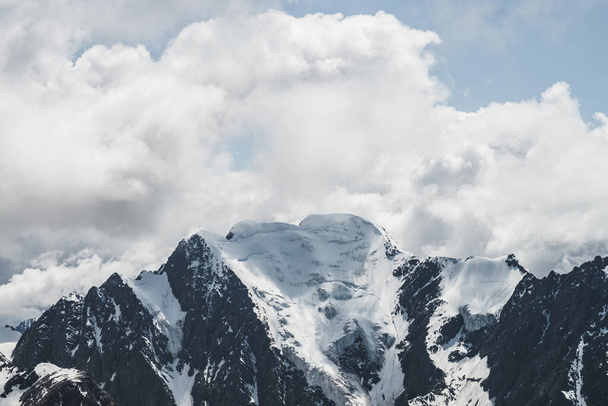 Atmosferik minimalist alp manzarası karlı dağ zirvesinde asılı devasa bir buzulla. Buzul sınırında büyük bir balkon. Karlı dağların üzerindeki bulutlu gökyüzü. Yüksek irtifada görkemli manzara. - Fotoğraf, Görsel