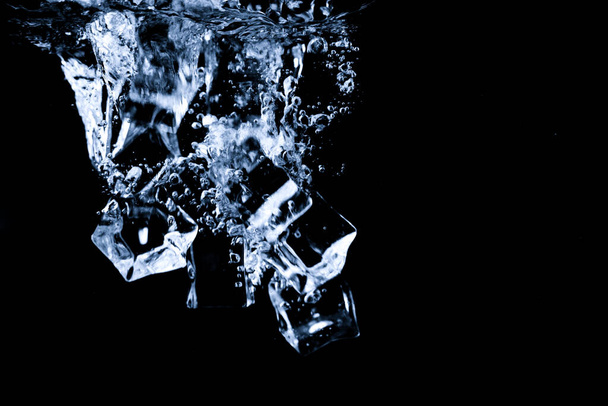 Water splash abstract shape with ice cubes isolated on black background. - Photo, Image