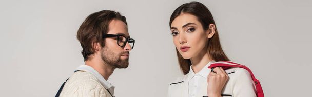 brunette woman looking at camera near man in eyeglasses isolated on grey, banner - Photo, Image