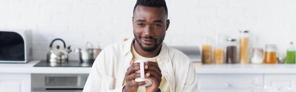 Χαρούμενος Αφροαμερικάνος που κρατάει ένα φλιτζάνι καφέ, πανό - Φωτογραφία, εικόνα