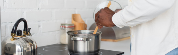 vue recadrée du jeune homme afro-américain cuisinant dans la cuisine, bannière - Photo, image