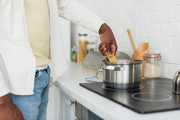 cropped view of young african american man cooking spaghetti in kitchen - Foto, Imagen