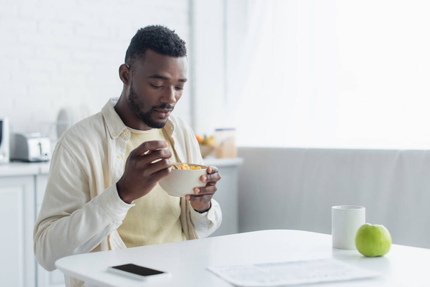 african american man holding bowl while having breakfast  - Foto, afbeelding