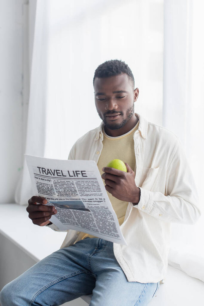 african american man holding apple and reading travel life newspaper  - Fotoğraf, Görsel