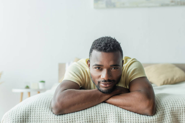 bearded african american man in t-shirt lying on bed - Фото, изображение