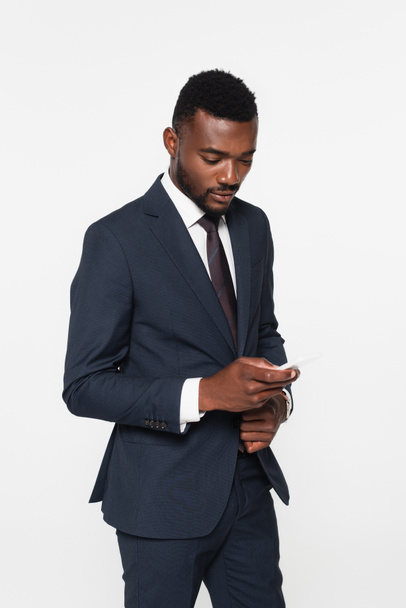 homme d'affaires afro-américain barbu en costume de messagerie sur smartphone isolé sur gris - Photo, image