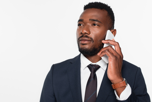 homme d'affaires afro-américain en costume ayant une conversation téléphonique isolé sur gris - Photo, image