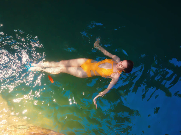 Een meisje zwemt in het turkoois water van een schaduwrijke kloof stralend in de zon - Foto, afbeelding