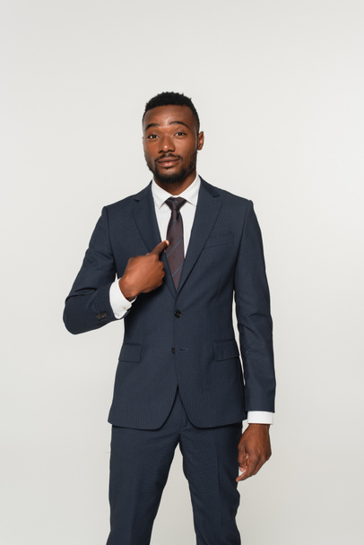 hombre de negocios afroamericano en traje apuntando con el dedo a sí mismo aislado en gris - Foto, Imagen