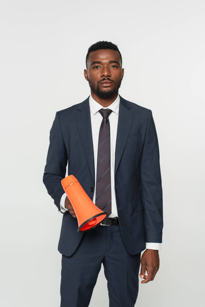african american businessman in suit with tie holding megaphone isolated on grey - Foto, immagini