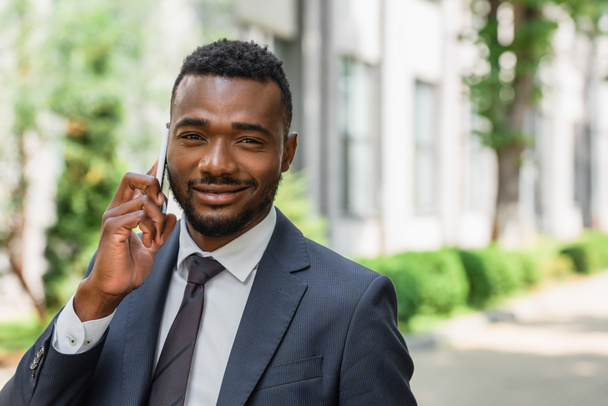 iloinen afrikkalainen amerikkalainen liikemies puhuu matkapuhelimella ulkopuolella - Valokuva, kuva