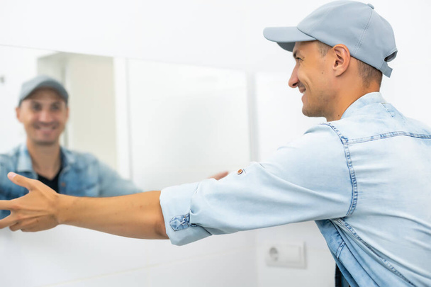 Handyman installing mirror in bathroom. - Photo, Image