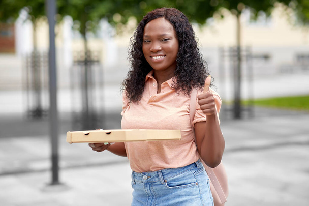 africaine étudiant fille avec pizza montrant pouces vers le haut - Photo, image