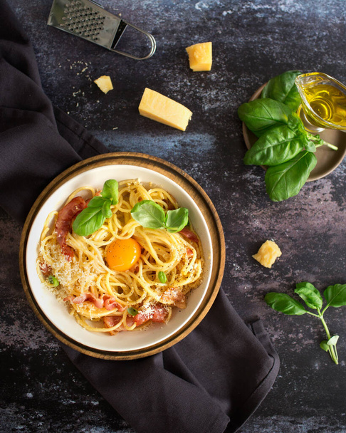Italská kuchyně. Těstoviny carbonara se slaninou a vejcem. Špagety s parmezánem a bazalkou. Italská večeře. Italské jídlo na tmavém pozadí. Olivový olej - Fotografie, Obrázek
