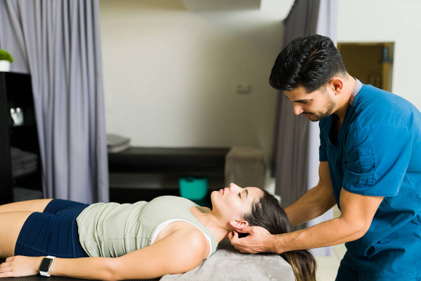 Schöne Physiotherapeutin gibt einer jungen Patientin in der Klinik eine Nackenmassage - Foto, Bild