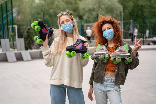 young roller skaters in medical masks looking at camera outdoors - Zdjęcie, obraz
