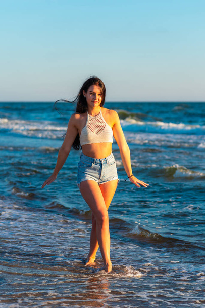 Красива сексуальна дівчина на морському пляжі в повсякденному одязі дивиться на камеру на заході сонця. Крупним планом модна дівчина. Красивий портрет моделі зовні
. - Фото, зображення