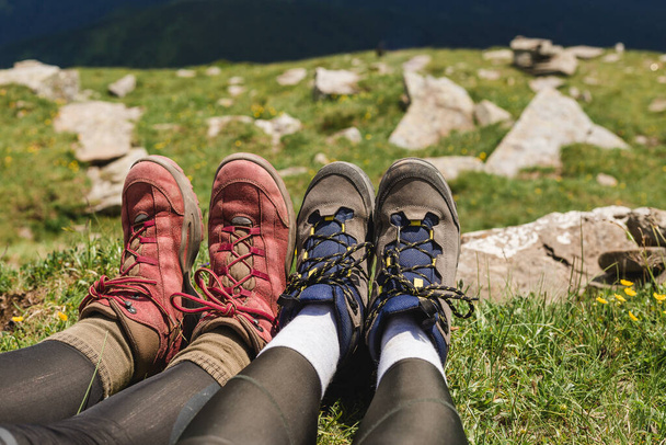 Мандрівники парять пішохідні черевики на красивому гірському ландшафті. Туризм або концепція свободи. Ноги мандрівника, що сидить на високій вершині гори у подорожах
. - Фото, зображення