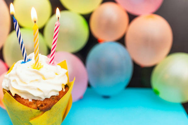 Syntymäpäivä cupcake.Pastel keltainen syntymäpäivä cupcake kynttilä ja hämärtynyt ilmapallot.värikäs syntymäpäivä cupcake värillinen candle.Closeup, kopioi space.Birthday käsite. - Valokuva, kuva