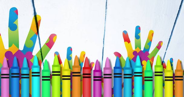 Image of colourful crayons over hands formed with puzzles. autism and learning difficulties awareness and support concept digitally generated image. - Фото, изображение