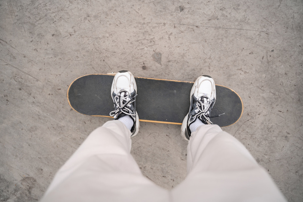 top view of cropped man in sneakers standing on skateboard outdoors - Fotoğraf, Görsel