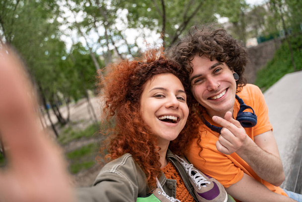 curly, happy man and woman taking selfie in park - Фото, изображение