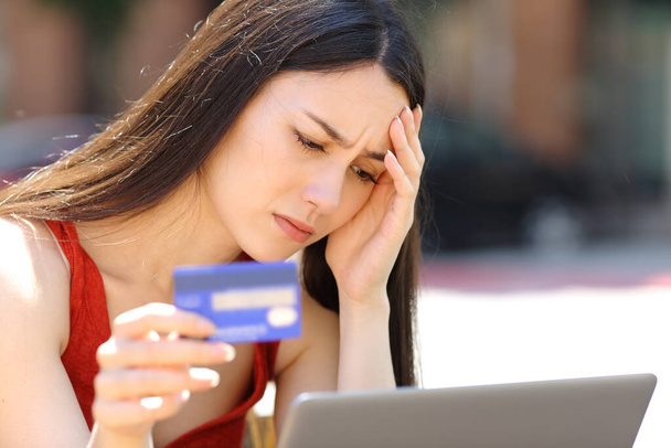 心配している女性が路上でクレジットカードやラップトップでオンラインで購入する問題を抱えている - 写真・画像