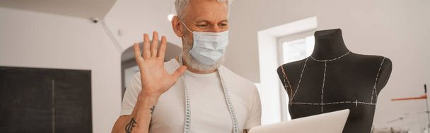 Designer in medical mask having video call near mannequin, banner  - Photo, Image