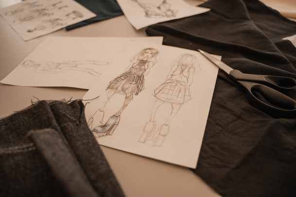 Ρούχα και σκίτσα στο τραπέζι σε στούντιο σχεδιαστών  - Φωτογραφία, εικόνα