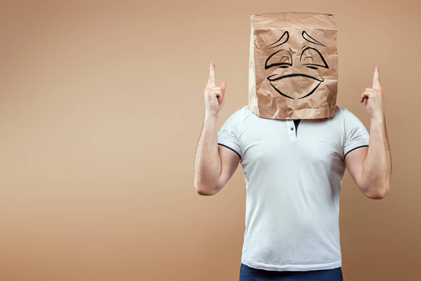 Men put a paper bag on their heads with a smiling face and show thumbs up. Isolate on yellow background, images are easy to crop for use anywhere, copy space. - Photo, Image