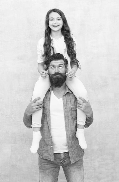Growing mustache is fun. Little daughter twist fathers moustache. Happy family grey background. Bearded man ride child on shoulders. Family values. Trust relationship. Love and care - 写真・画像