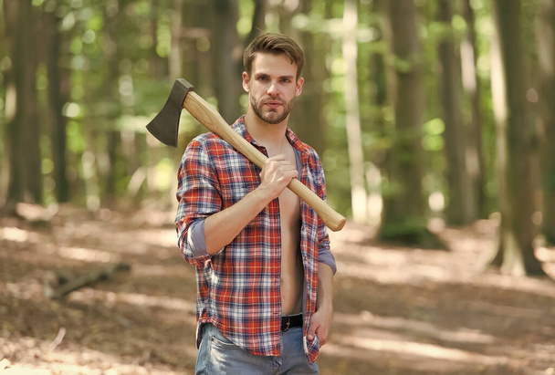 Unleashing your inner lumberjack. Handsome guy carry axe on natural landscape. Summer vacation. Nature travel. Natural environment. Ecology and ecosystem. Tree chopping. Trip into forest - Фото, изображение
