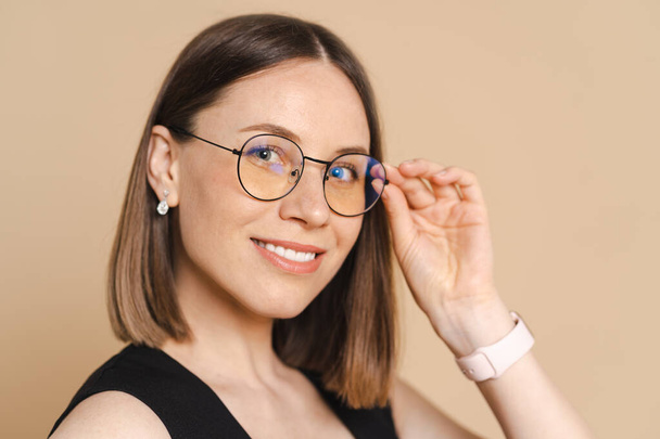 Portrait of a young business woman with glasses on a beige background - Foto, afbeelding