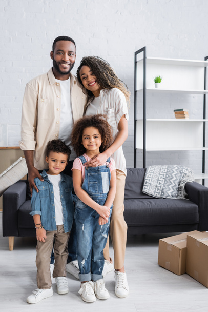 happy african american couple with kids looking at camera while standing in new apartment - 写真・画像