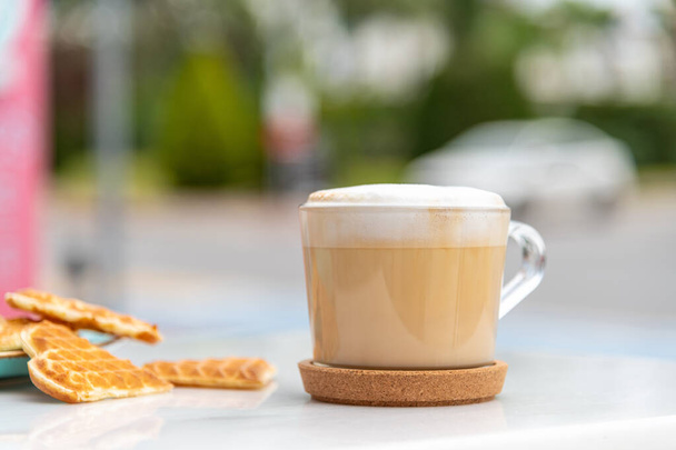 Kafenin bahçesindeki mermer masada kahve ve kalp waffle 'ı. - Fotoğraf, Görsel