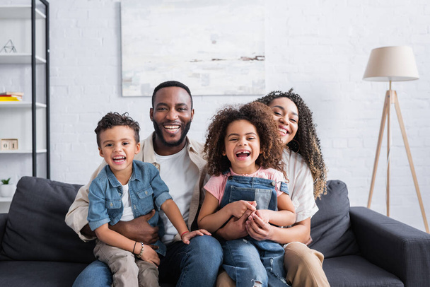 familia afroamericana emocionada riendo en el sofá en casa - Foto, imagen