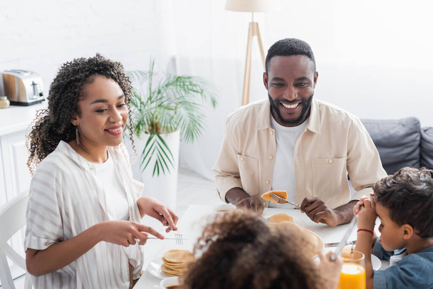 Пара афроамериканців посміхається під час сніданку з розмитими дітьми. - Фото, зображення