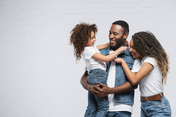 excited african american family looking at each other and hugging on grey - Foto, immagini